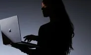 Silhouette a unei persoane folosind un laptop modern într-un mediu întunecat.