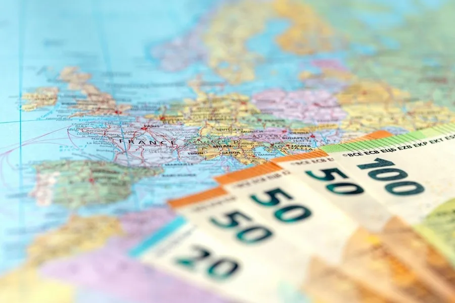 Harta Europei cu bancnote de diferite valori pe fundal.