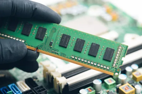 Placă de memorie RAM ținută în mână, detaliu tehnic al componentelor PC.