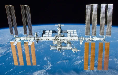 Stația Spațială Internațională orbitând Pământul, cu panouri solare vizibile.