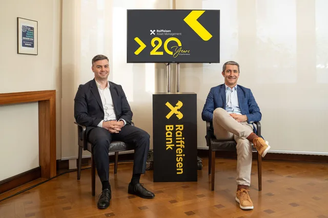 Două persoane discutând despre creșterea activelor administrate de Raiffeisen.