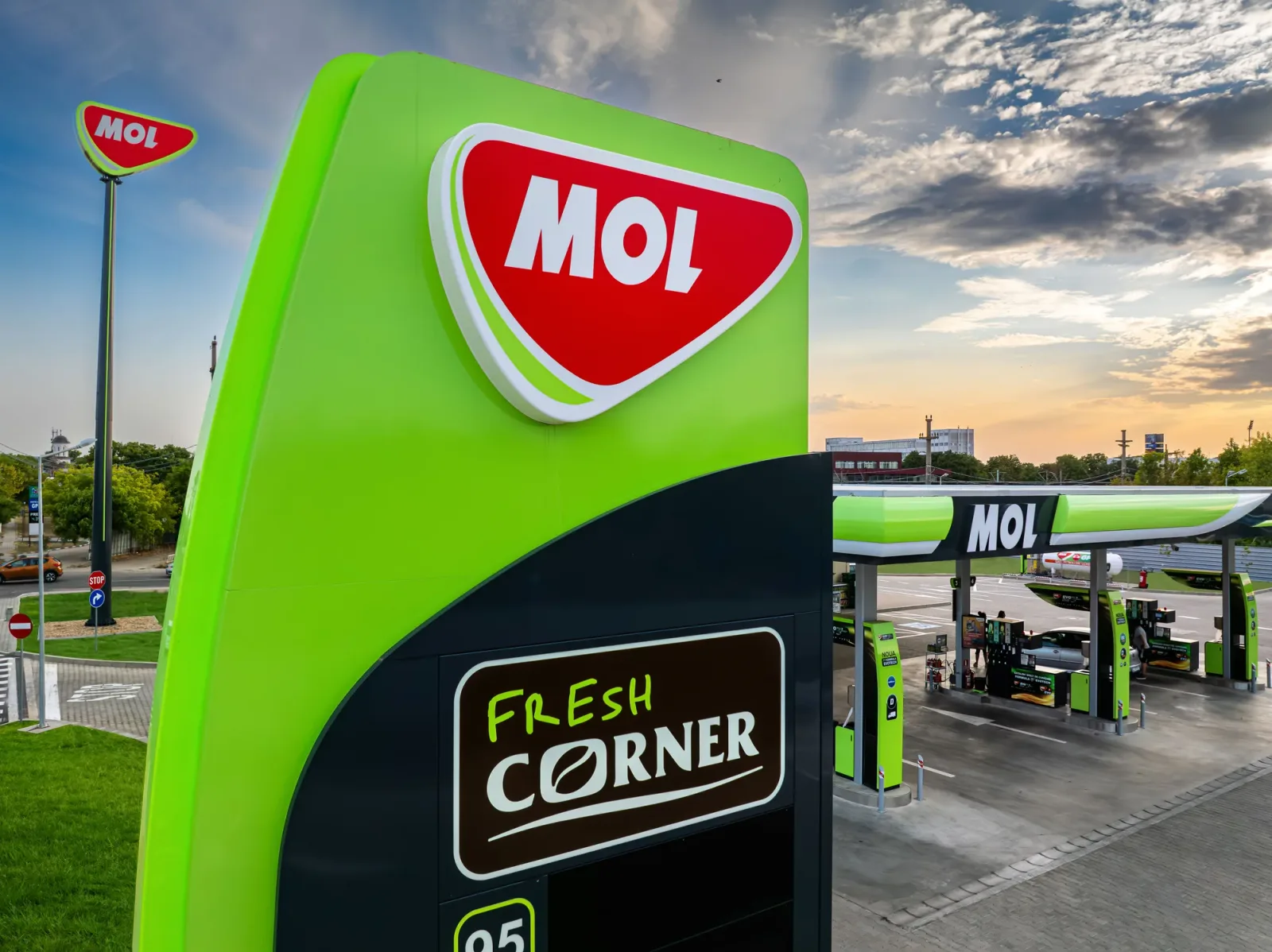 Stație de alimentare Lukoil cu mașini parcate și cer senin.