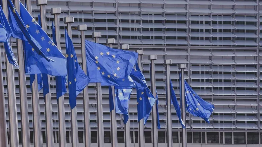 Steaguri ale Uniunii Europene fluturând în fața unei clădiri moderne.