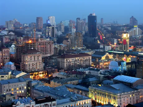 Vedere panoramică a orașului Kiev la apus, cu clădiri și lumini strălucitoare.