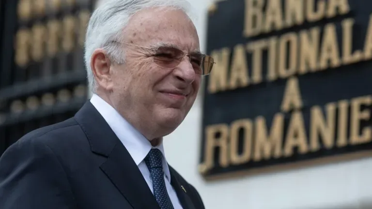 Un bărbat zâmbind în fața Băncii Naționale a României.