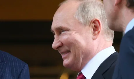 Vladimir Putin zâmbind în timpul unei întâlniri oficiale.