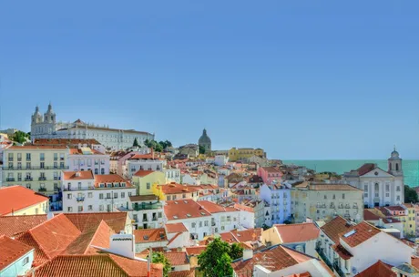 Peisaj urban din Lisabona, cu clădiri colorate și ocean în fundal.