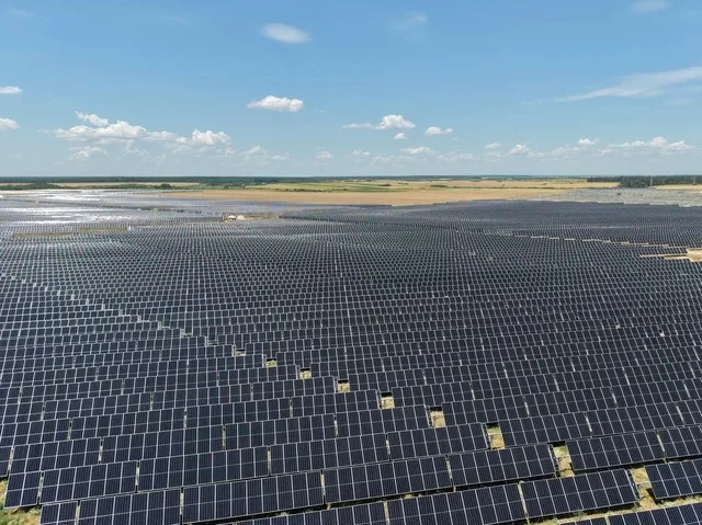 Panouri solare amplasate pe un câmp vast, sub un cer senin.