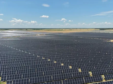 Panouri solare amplasate pe un câmp vast, sub un cer senin.