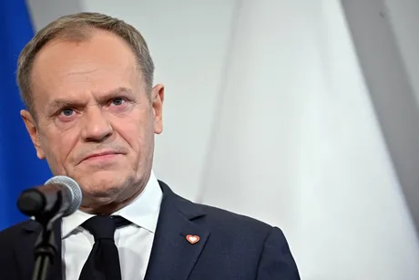 Donald Tusk zâmbește în timpul unei conferințe de presă, discutând despre candidaturi politice.