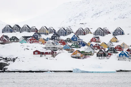 Case colorate pe fundalul peisajului arctic din Groenlanda, acoperit de zăpadă.