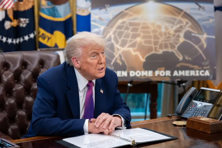 Donald Trump discutând la biroul său, cu harta Americii în fundal.