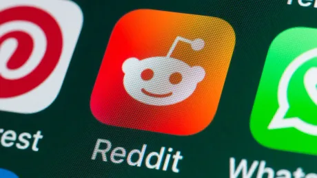 Logo-ul Reddit pe un ecran de telefon mobil, cu fundal colorat.
