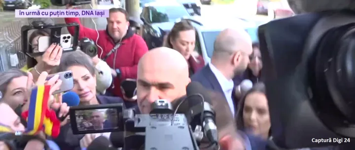 Premierul Ilie Bolojan părăsește sediul DNA Iași înconjurat de jurnaliști.
