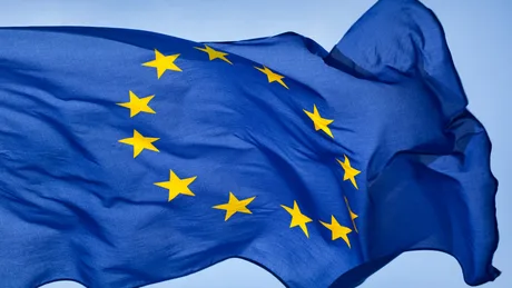 Steagul Uniunii Europene fluturând în vânt, simbol al cooperării între state.