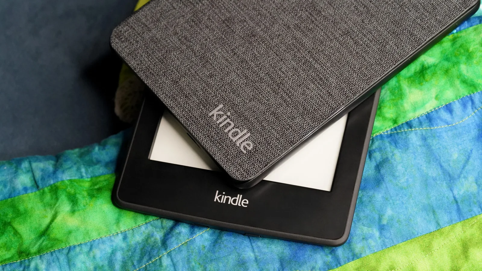 Dispozitive Kindle așezate pe o pătură colorată, simbolizând utilizarea pe termen lung.