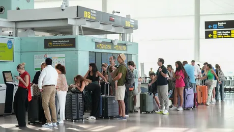 Oameni așteptând la un ghișeu de check-in la aeroport.