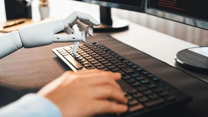 Un robot interacționează cu un computer, simbolizând inteligența artificială.