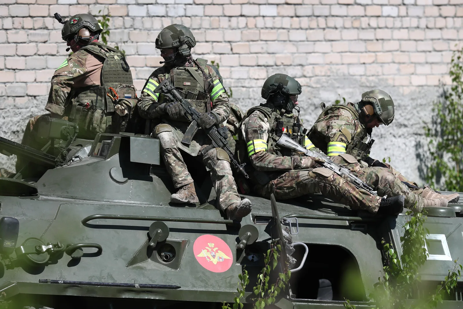 Soldați în echipament militar pe un vehicul blindat, pregătiți pentru acțiune.