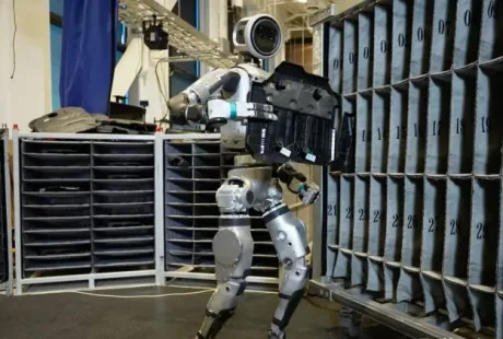 Robotul Atlas manipulează un obiect în mediu industrial.