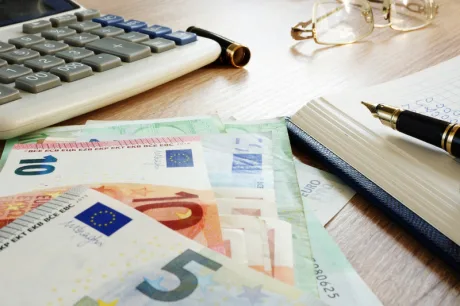 Bancnote euro și instrumente de scris pe birou.