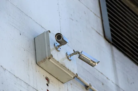 Camere de supraveghere montate pe un perete, expuse riscurilor de securitate.