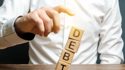 Blocuri de lemn cuvântul DEBT, simbolizând datoria.