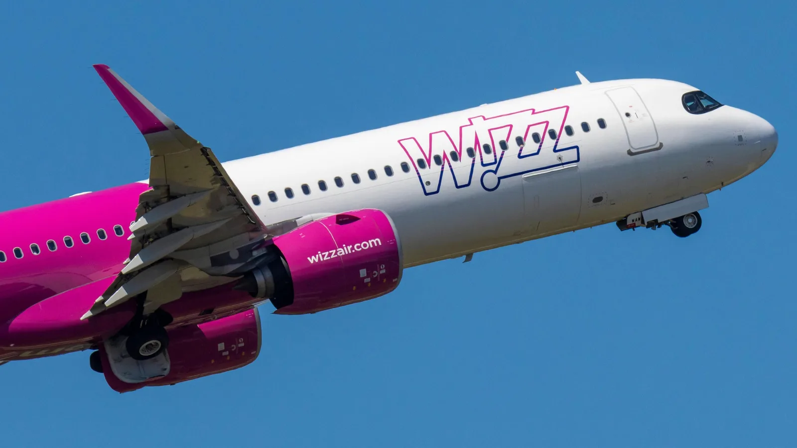 Aeronava Wizz Air în zbor, cu un cer senin în fundal.