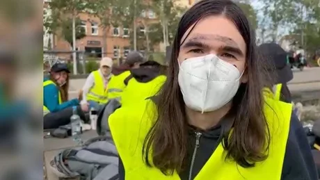 Activist protestatar în vestă galbenă, discutând despre blocadele anti-AfD.