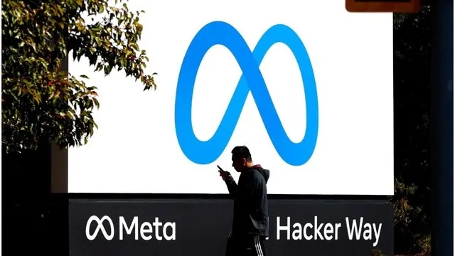 Logo-ul Meta pe un panou publicitar, cu o persoană în față.