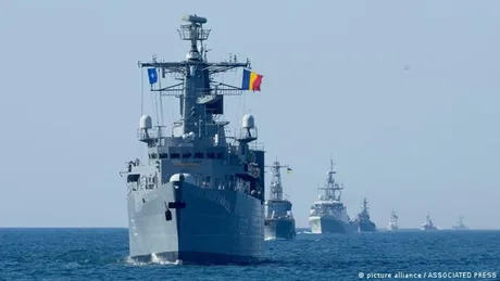 Nave militare în exercițiu pe mare, simbolizând cooperarea internațională.
