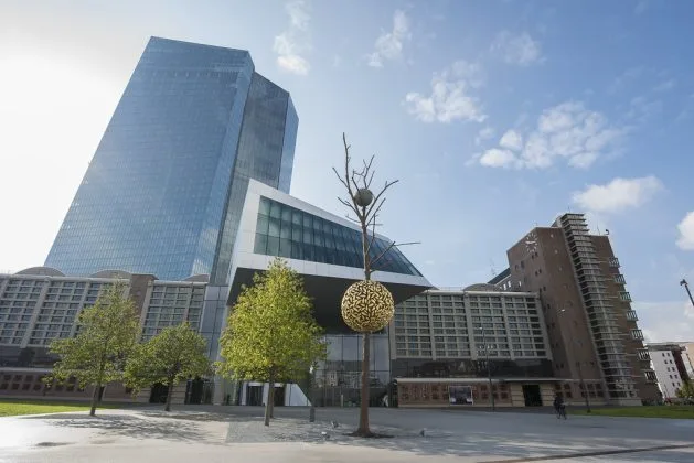 Clădire modernă a Băncii Centrale Europene în Frankfurt, cu copaci verzi în față.