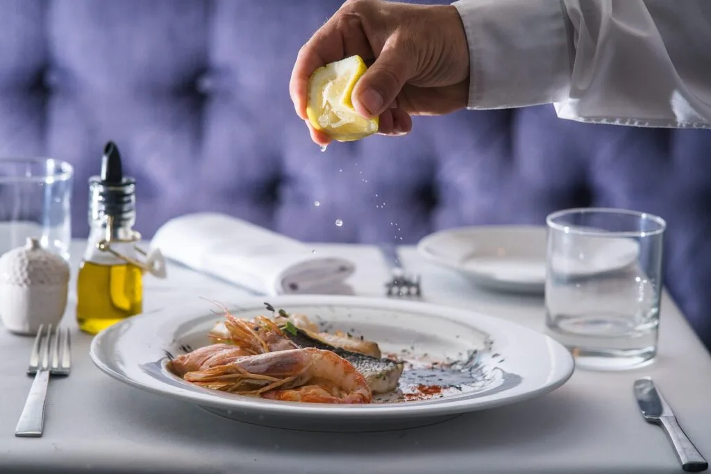 Mâncare gourmet servită elegant, cu fructe de mare și lămâie proaspătă.