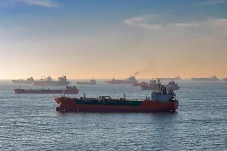 Vas de transport maritim pe fundalul unei mări agitate, cu nave ancorate.
