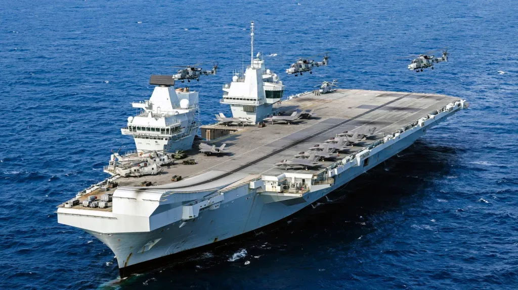 Portavion britanic navigând pe mare, cu elicoptere în zbor.