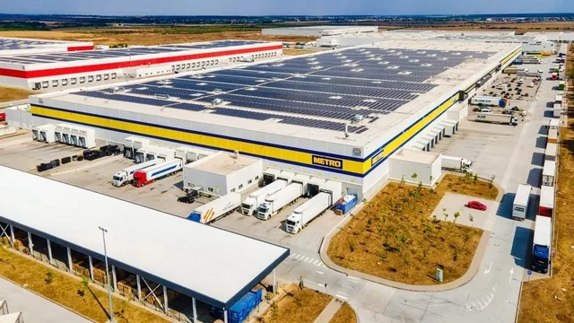 Depozit logistic modern cu panouri solare și camioane parcate.