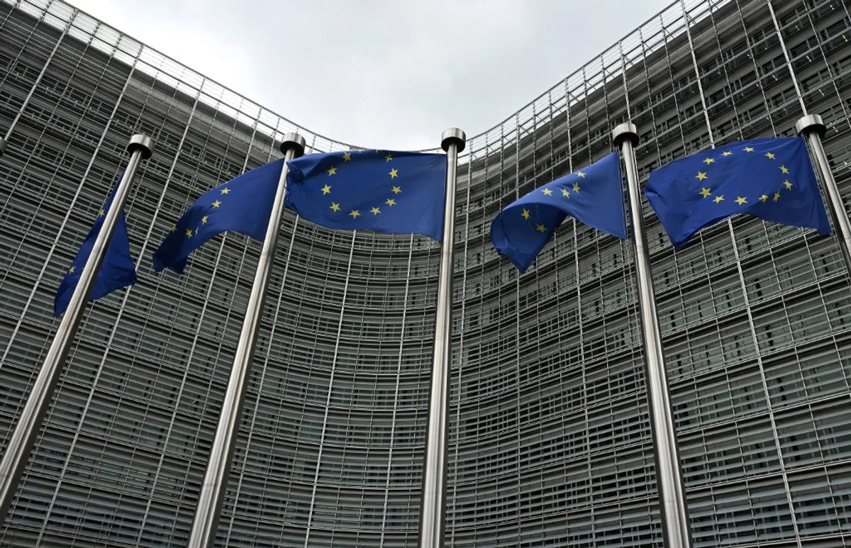 Sediul Uniunii Europene cu steaguri fluturând în vânt.