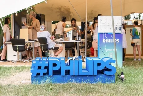 Activitate la un stand Philips, cu oameni interacționând în fundal.