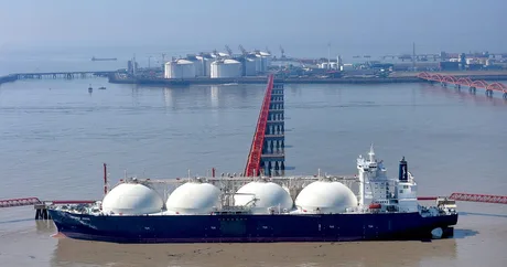Vapor de GNL ancorat în port, cu rezervoare în fundal.