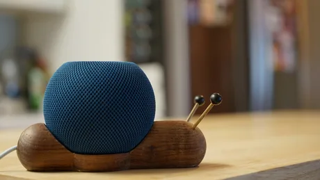 Un difuzor HomePod mini pe un suport creativ, cu aspect de melc.
