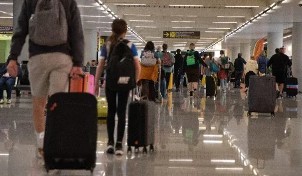 Oameni cu bagaje în aeroport, pregătiți pentru călătorie.