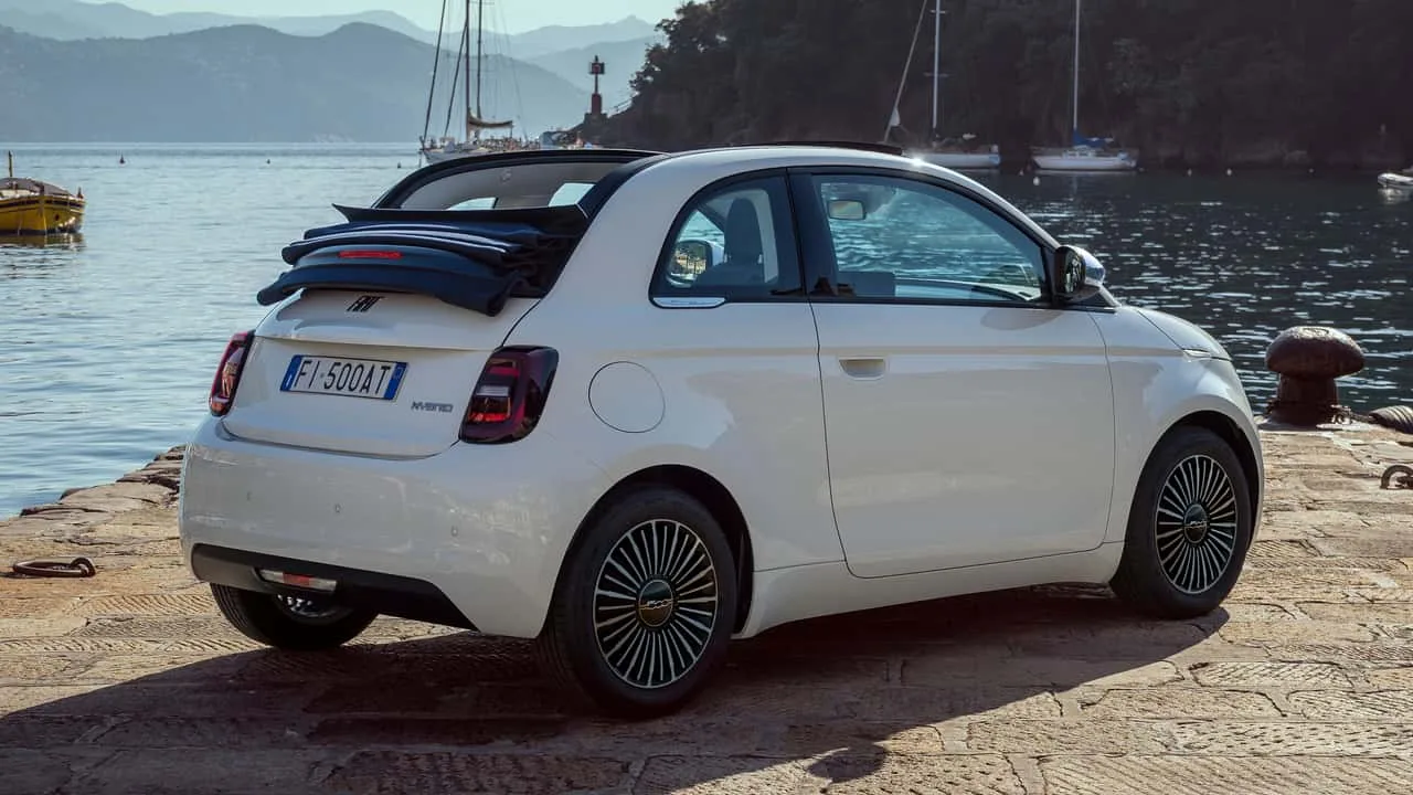 Fiat 500 Hybrid Dolcevita decapotabilă pe malul apei, cu plafon textil albastru.