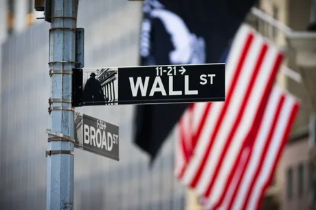 Strada Wall Street cu steaguri americane în fundal.