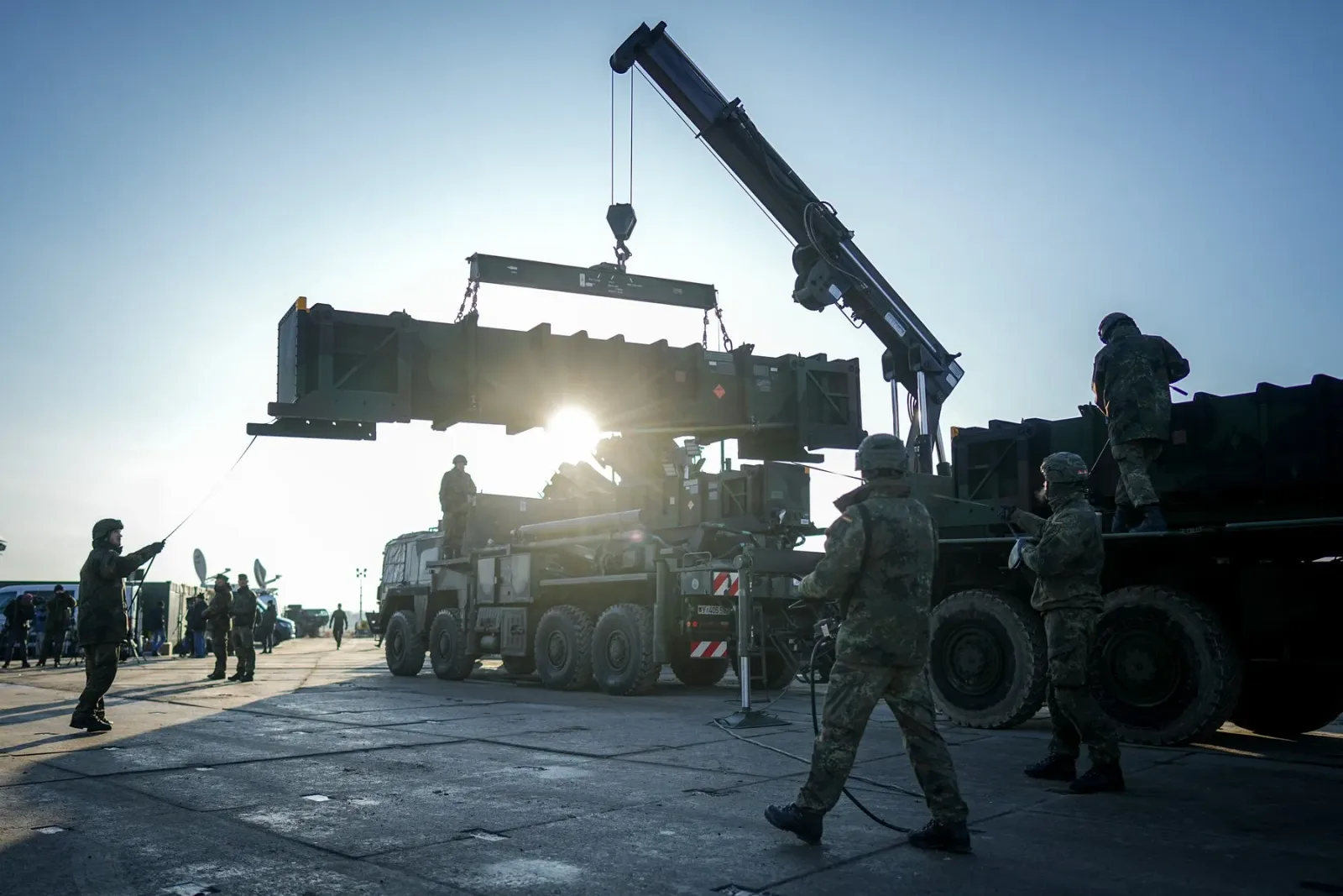 Soldați coordonează livrarea de echipamente militare pe un teren de desfășurare.