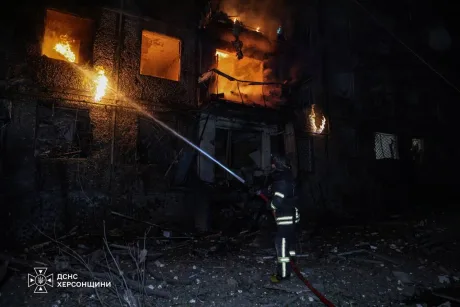 Pompier stingând flăcările la o clădire afectată de atacuri în Ucraina.