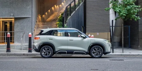 Un vehicul electric modern parcate pe o stradă urbană, cu arhitectură contemporană în fundal.