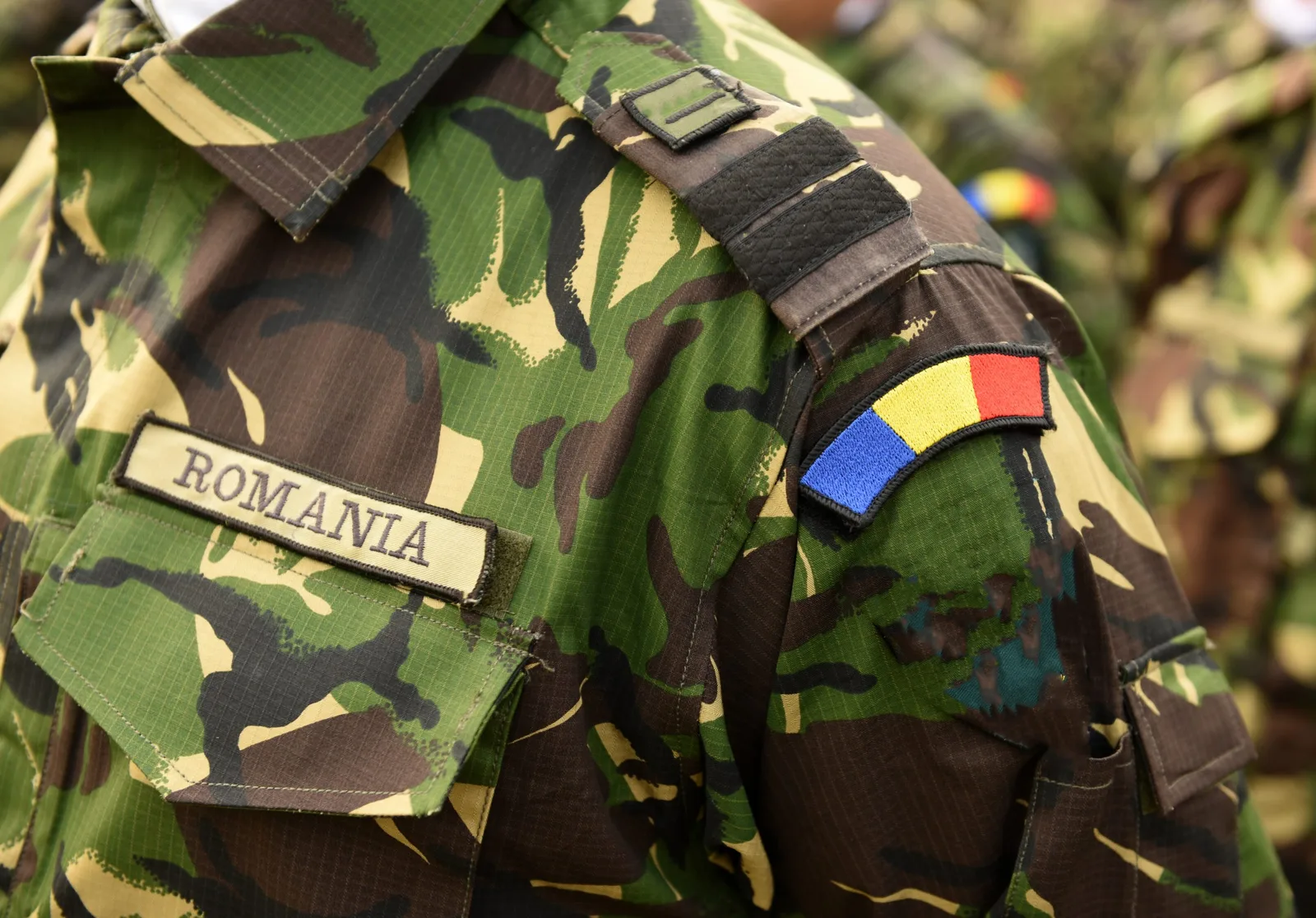 Uniformă militară românească cu insigna națională pe umăr.