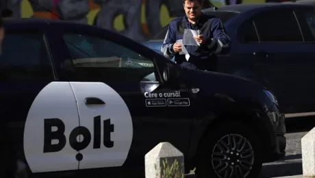 Un șofer Bolt așteaptă comanda în apropierea unei mașini.