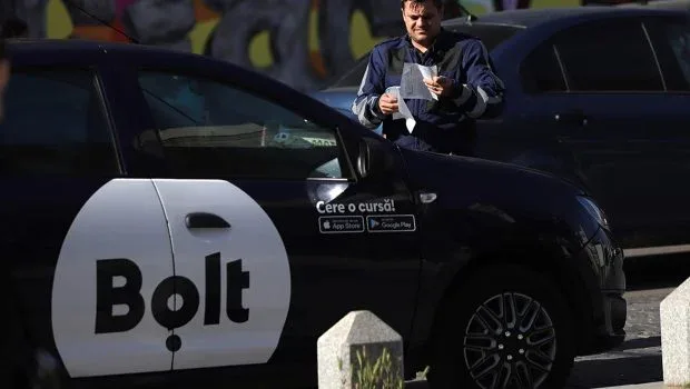 Un șofer Bolt așteaptă comanda în apropierea unei mașini.