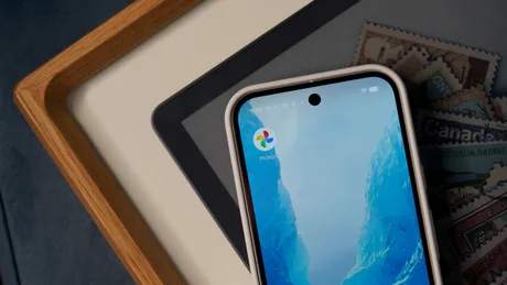 Aplicația Google Photos deschisă pe un telefon mobil, pe un fundal de birou.